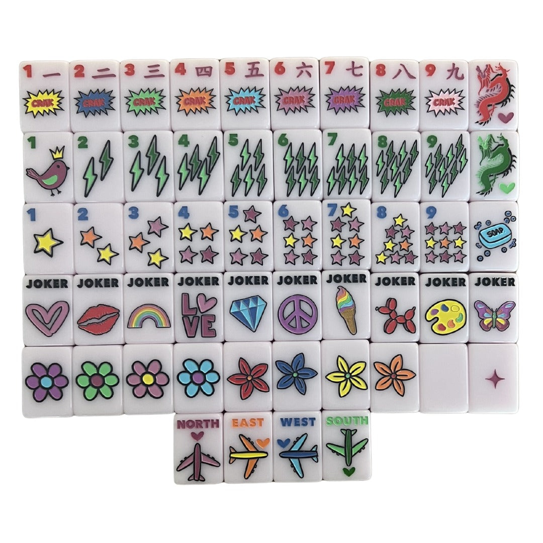 One of each Bespoke Mahjong x Corey Paige Color Crush Powder Pink tile: comic-burst craks, lightning bams, star dots, pop-art jokers, daisy flowers, and airplane winds on pale pink