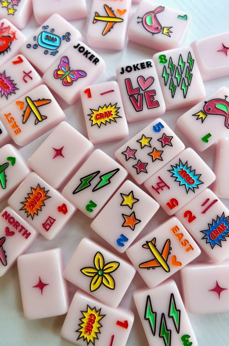 Close-up of scattered Corey Paige Color Crush Powder Pink tiles showing LOVE, lightning, star, and airplane designs