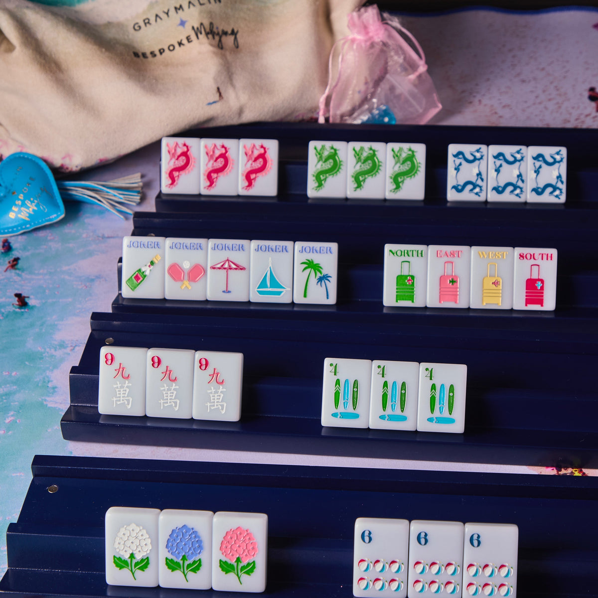 Gray Malin Beach Club Ocean Blue tiles on navy racks with the Gray Malin x Bespoke Mahjong tile bag; racks and mat sold separately