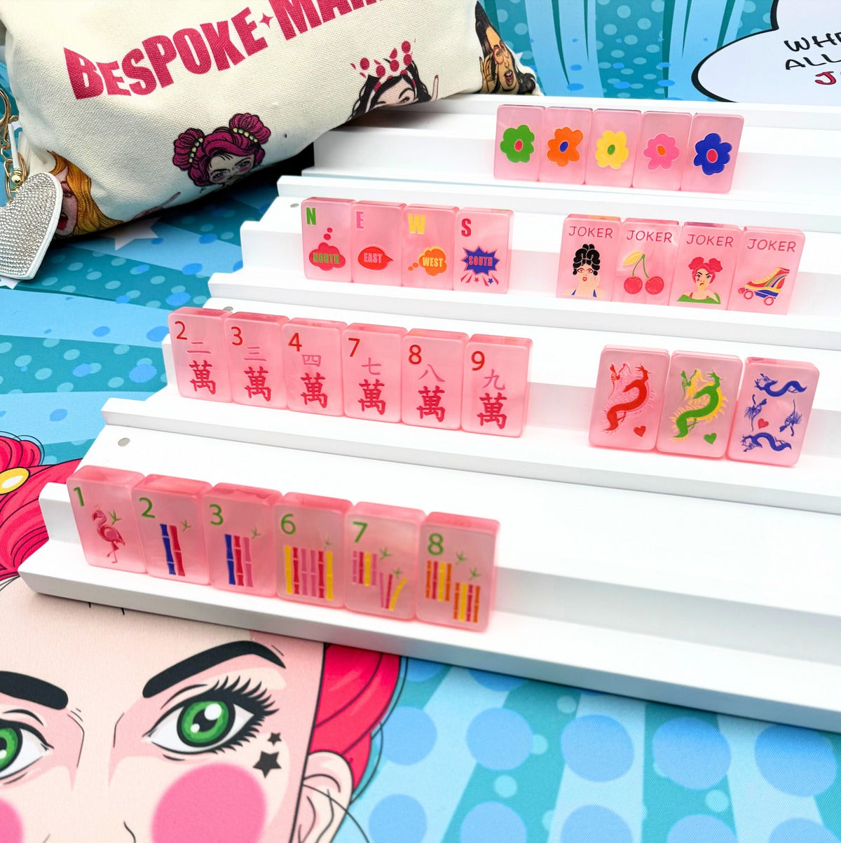 Bespoke Mahjong Pop Diva Cotton Candy Pink Pearl tiles on white racks showing daisy flowers, NEWS winds, pop-diva jokers, and heart dots; racks and mat sold separately