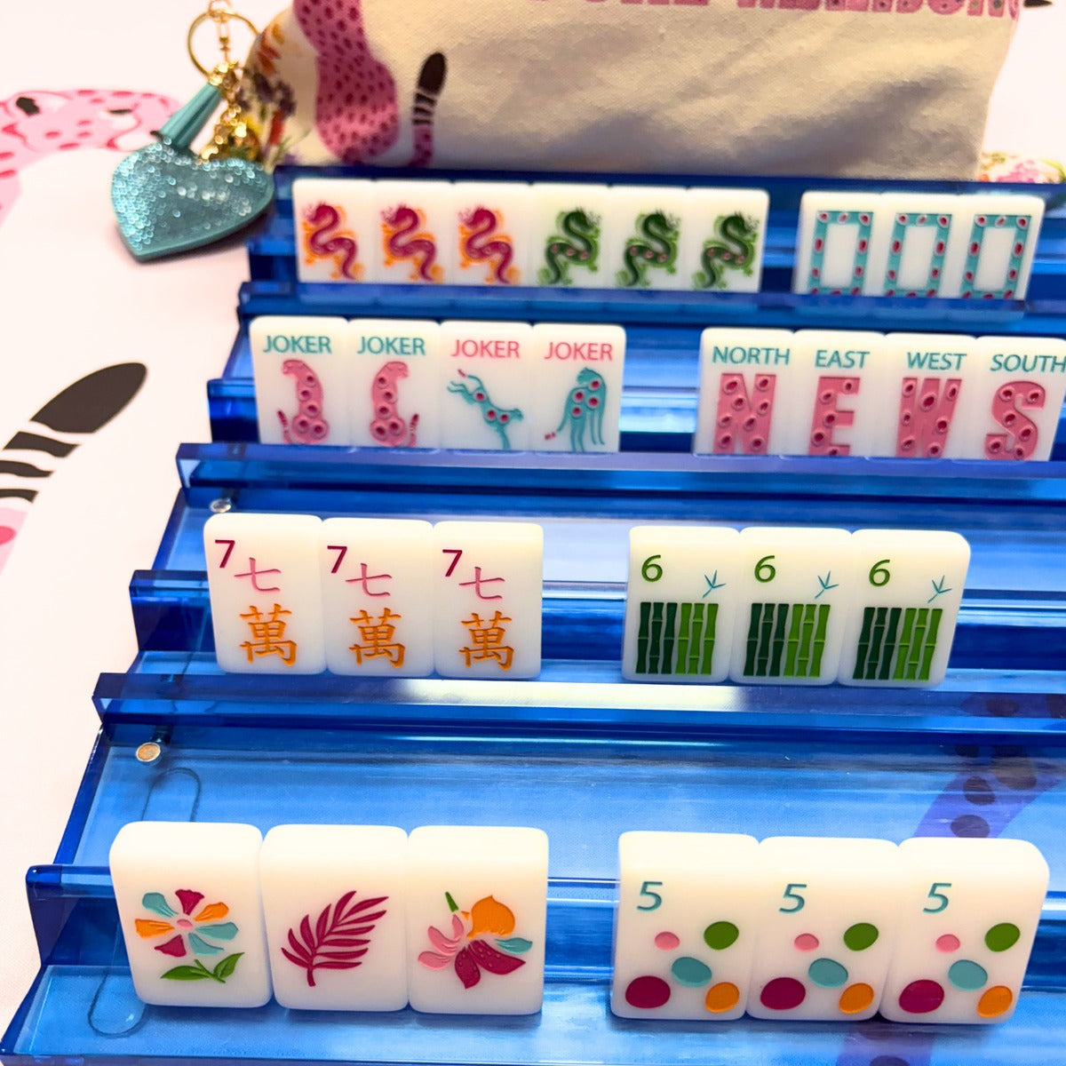 Springtime Safari Bright White tiles on blue racks showing dragons, jokers, NEWS winds, and flower tiles; racks and mat sold separately