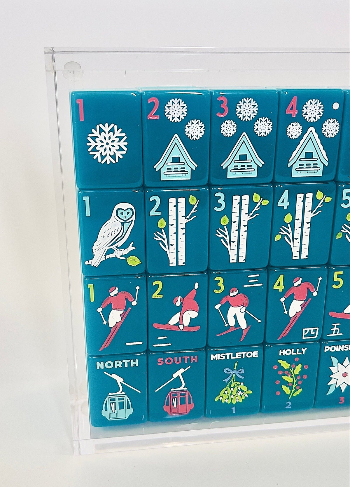 Close-up of Après Ski Club tiles in a clear acrylic display box showing the owl one bam and skier craks; display box sold separately