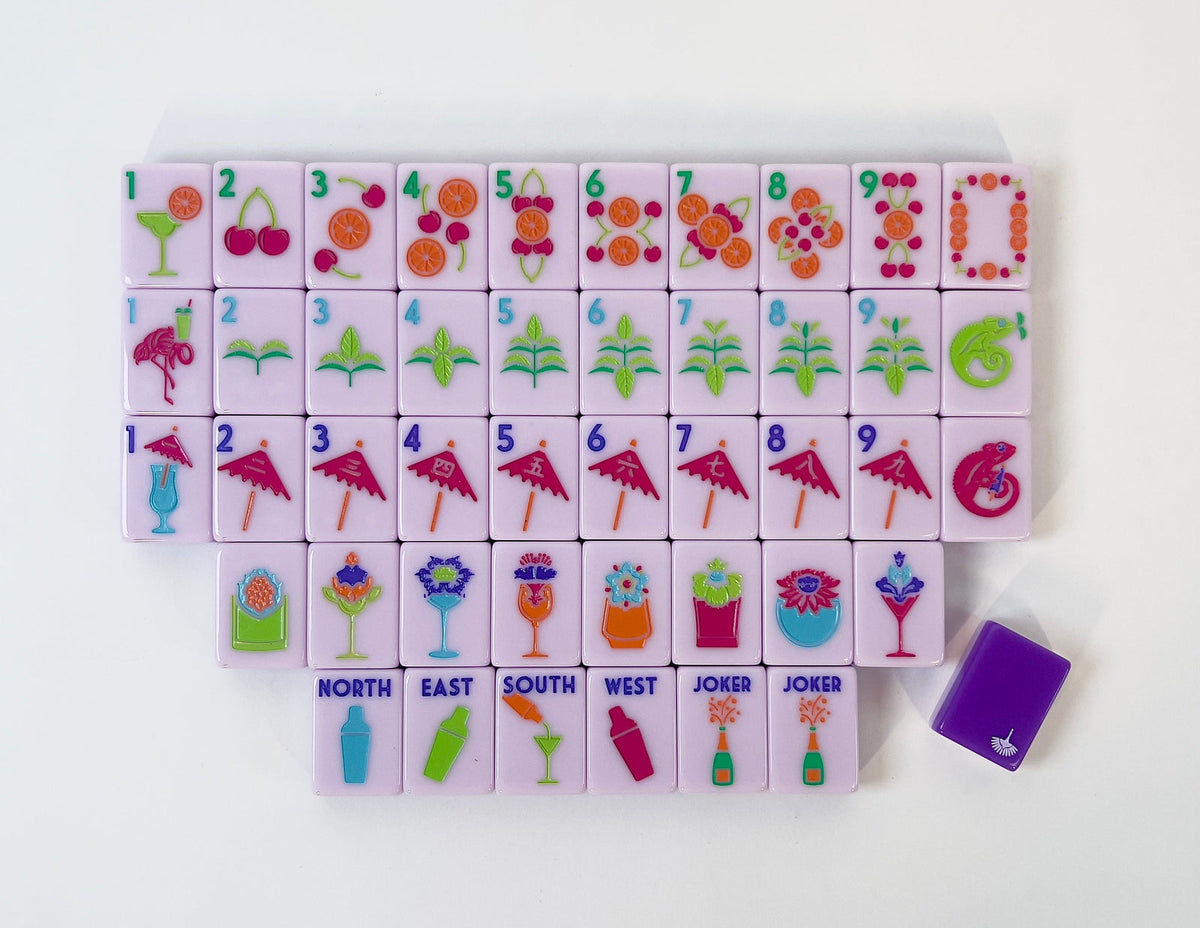 One of each Charleston Mahjong Club Cocktail Club 2.0 tile face laid out in rows: citrus dots, mint bams, umbrella craks, cocktail flowers, shaker winds, and champagne jokers, with a purple tile back