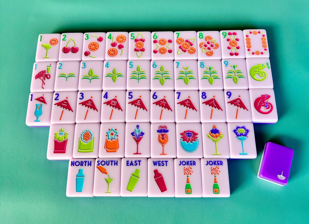 Cocktail Club 2.0 mahjong tiles laid out face up on a teal background, lavender faces with a purple tile back beside them