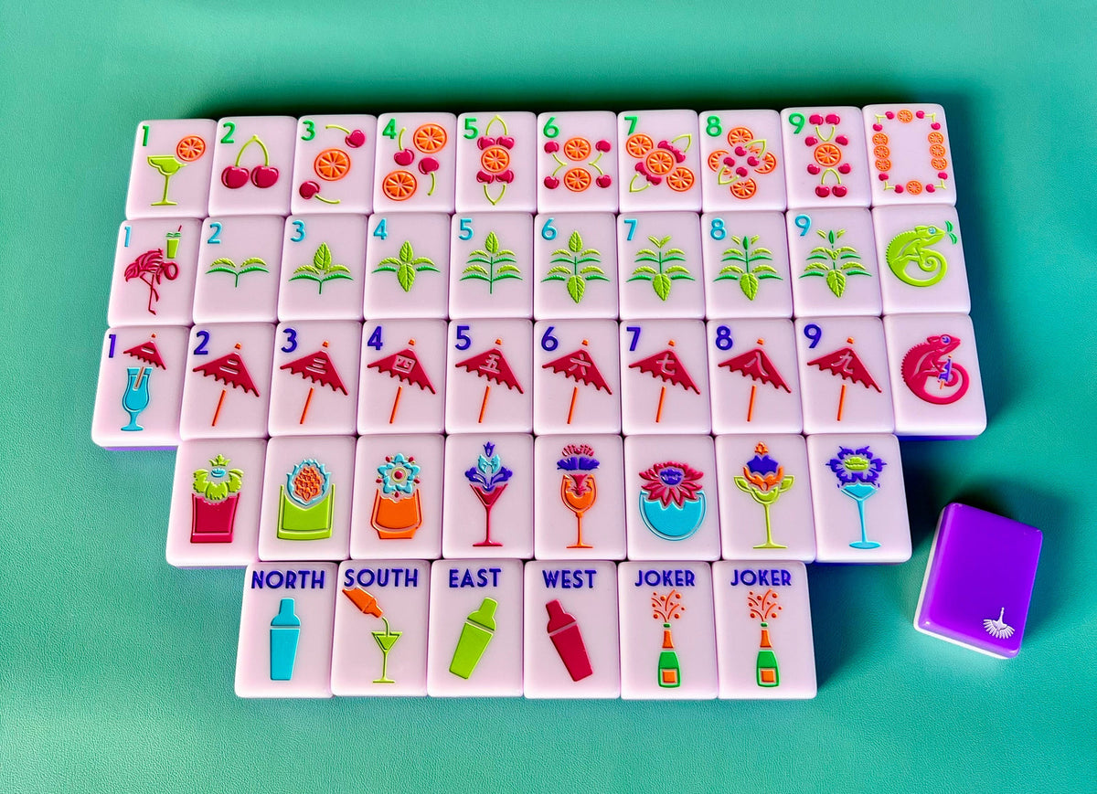 Cocktail Club 2.0 mahjong tiles laid out face up on a teal background, lavender faces with a purple tile back beside them