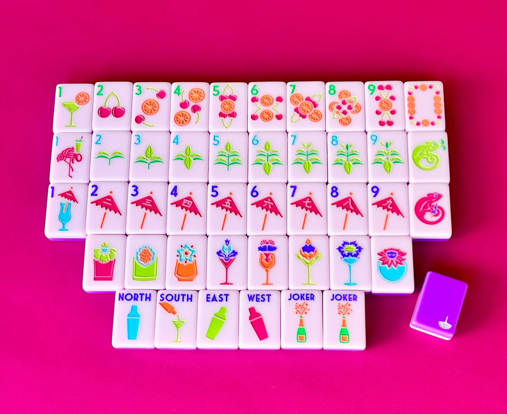 Cocktail Club 2.0 mahjong tiles laid out face up on a hot pink background, lavender faces with a purple tile back beside them