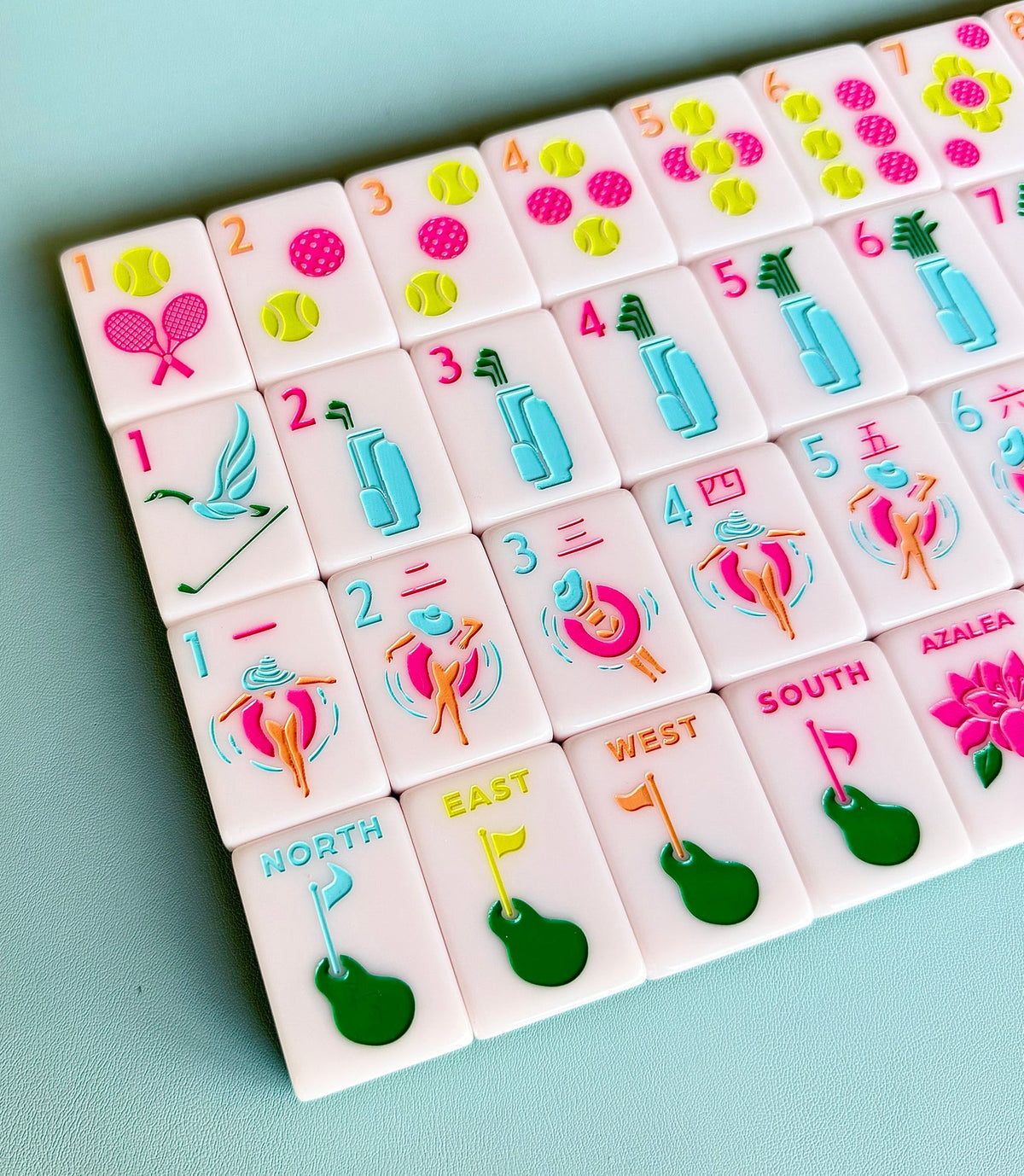 Angled close-up of Country Club mahjong tiles showing pink and yellow tennis-ball dots, blue golf-bag bams, and pool-float craks