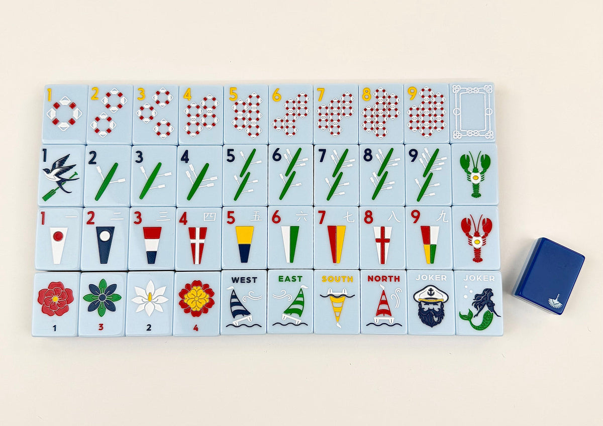 Charleston Mahjong Club Yacht Club tiles laid out face up in rows on a cream background, light blue faces with a navy tile back beside them