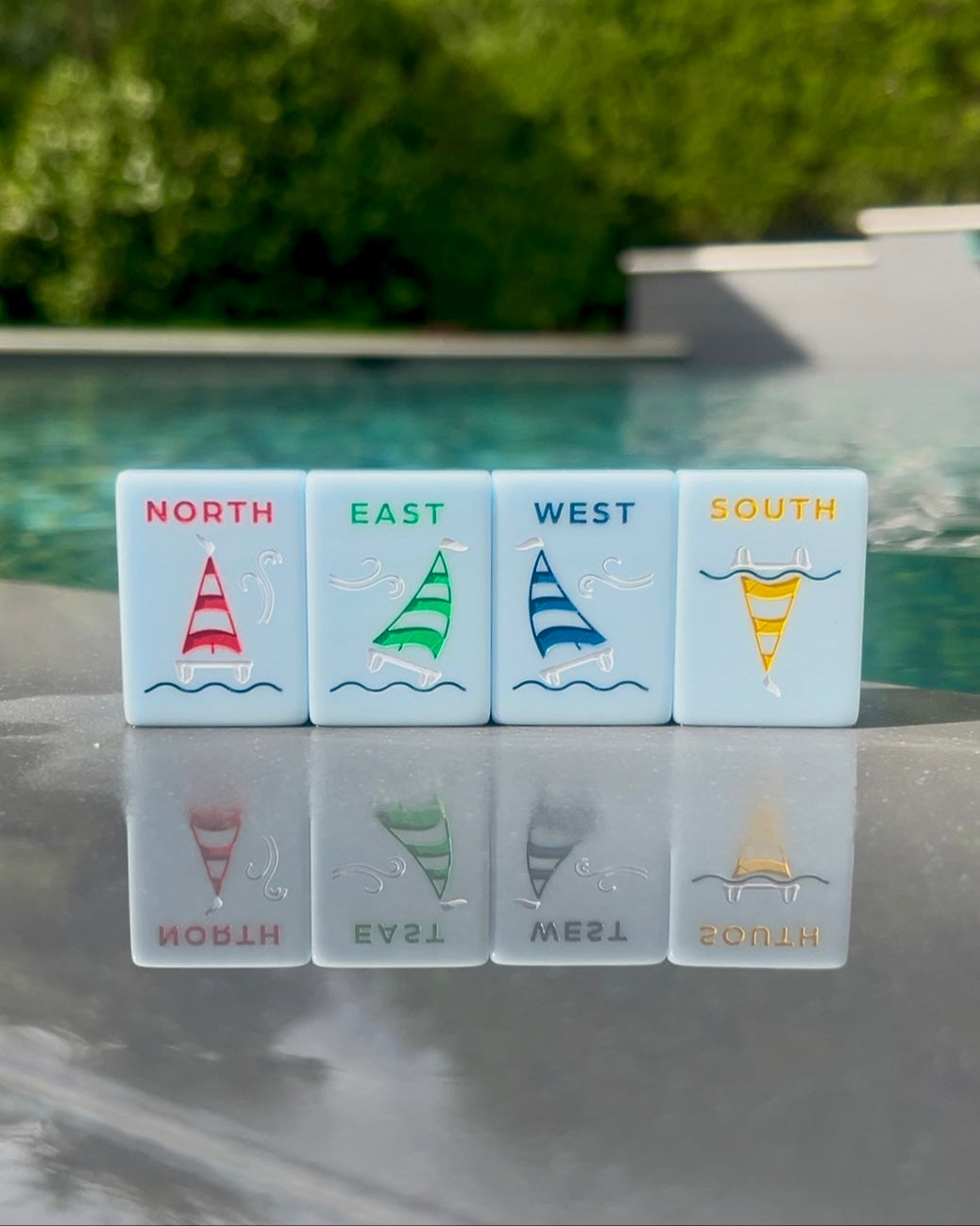 Yacht Club north, east, west, and south wind tiles with colored catamarans, standing beside a pool