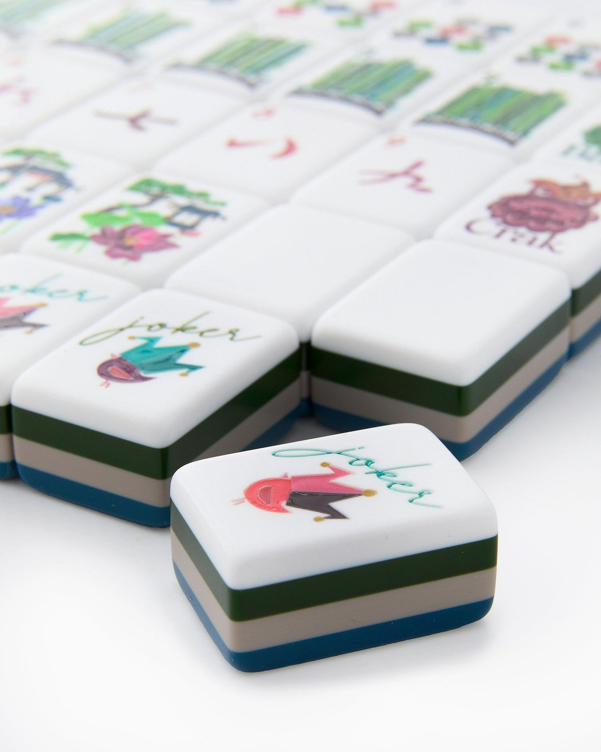 Close-up of Gatsby joker tiles with a bird in a jester's cap, showing the layered navy, green, and white tile edges
