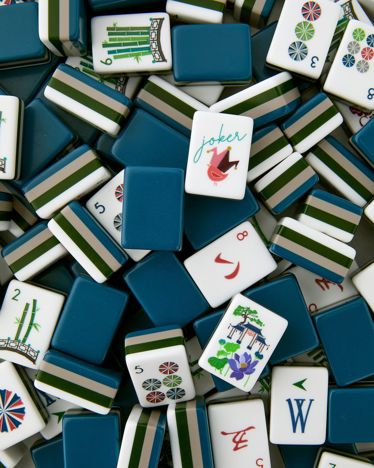 Oh My Mahjong Gatsby tiles piled loosely, navy backs striped with green and white beside white tile faces