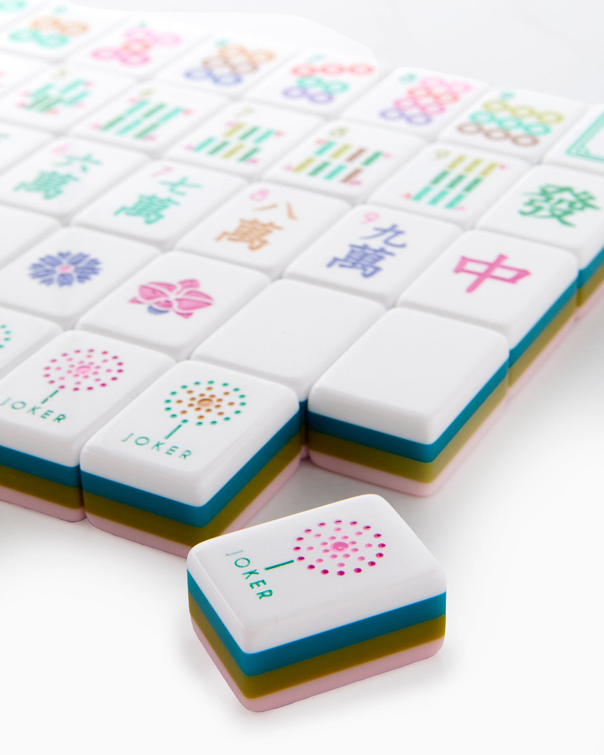 Close-up of La Fete joker tiles with a dandelion burst, showing the layered pink, olive, and teal tile edges
