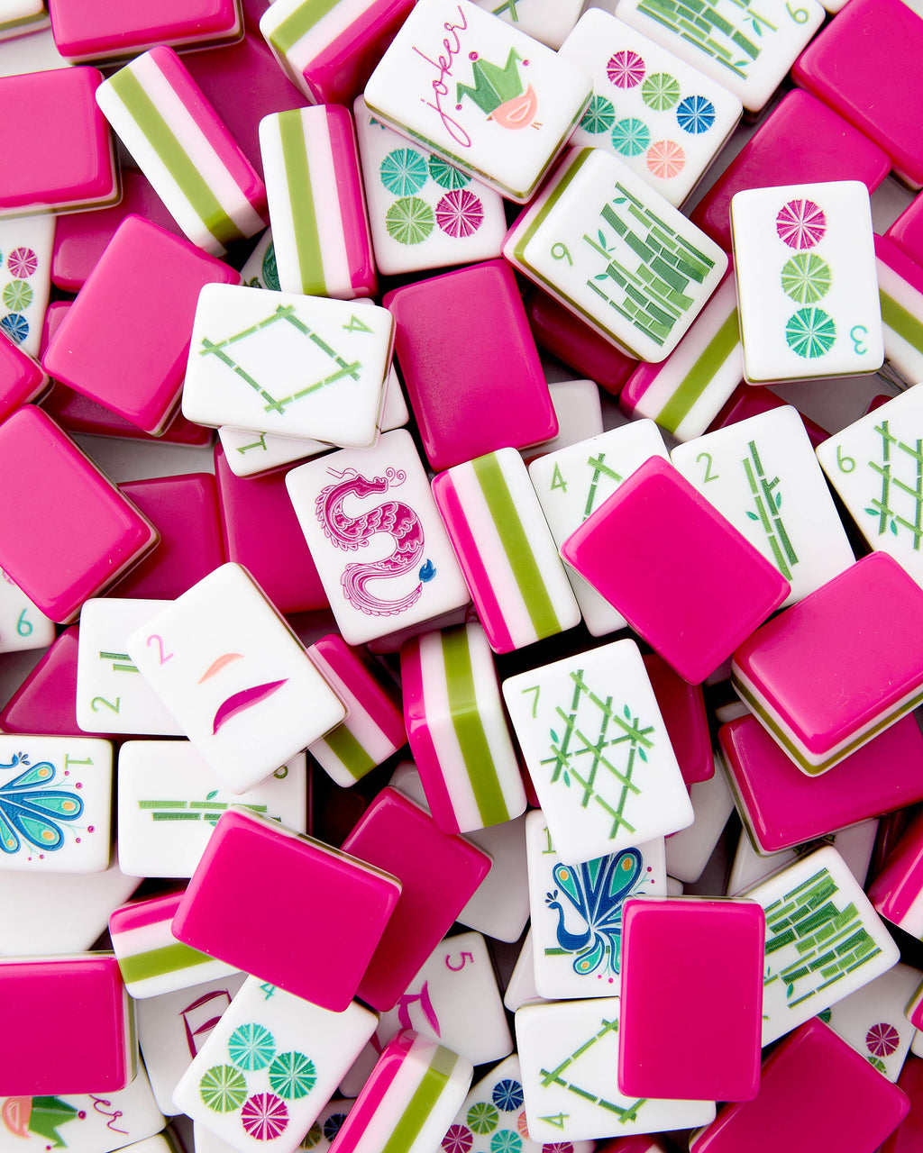 Oh My Mahjong Dandy tiles piled loosely, magenta backs striped with olive green and pale pink beside white tile faces