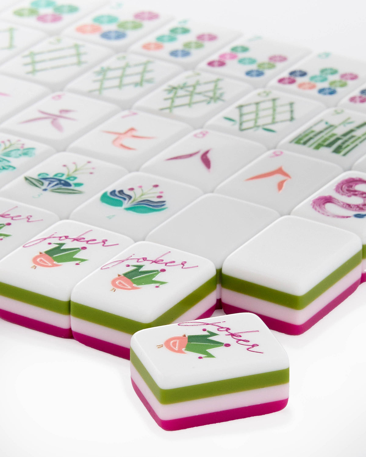 Close-up of Dandy joker tiles with a small crowned bird, showing the layered olive, pink, and magenta tile edges