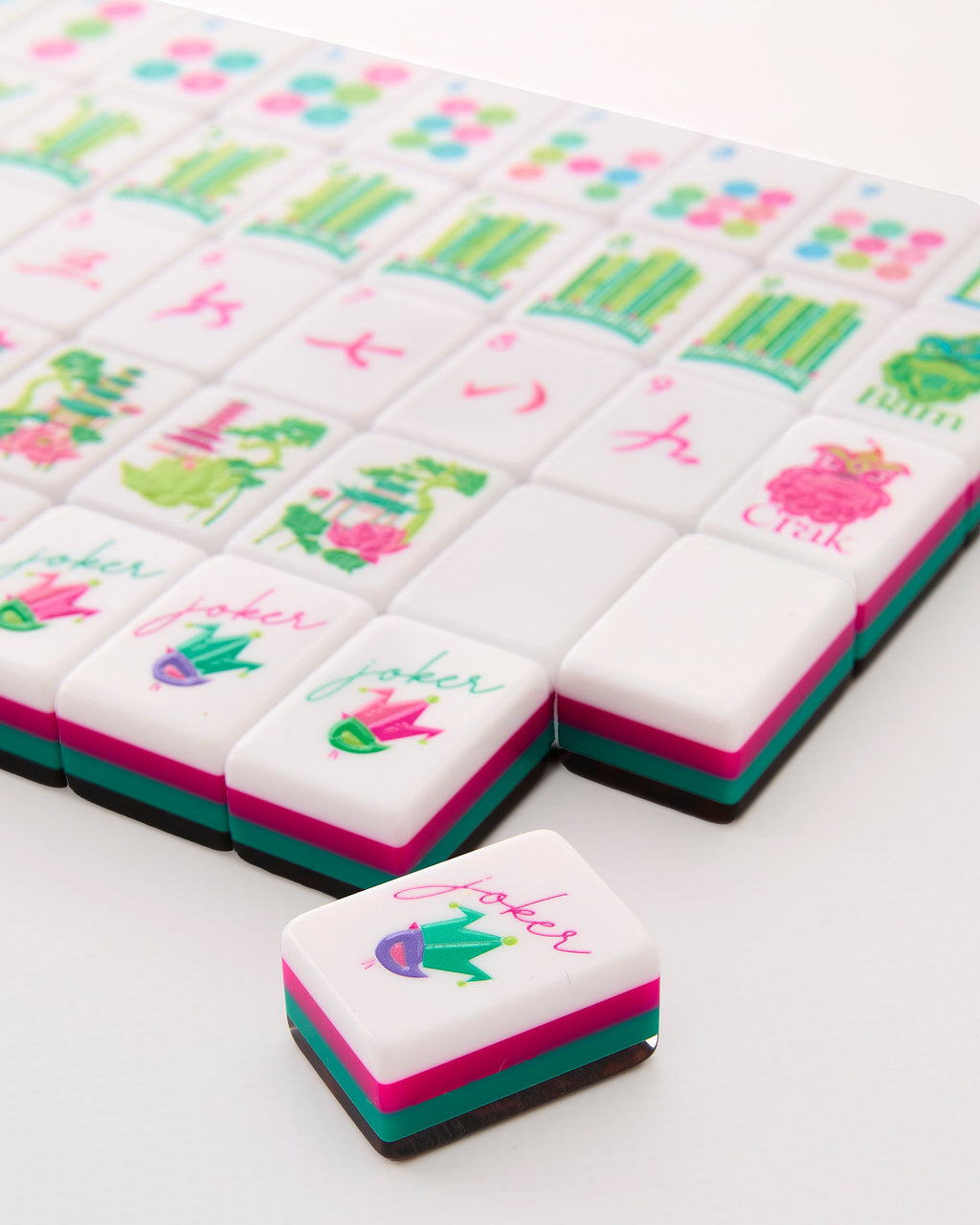 Close-up of Glow Wild joker tiles with a small crowned bird, showing the layered pink, teal, and tortoiseshell tile edges