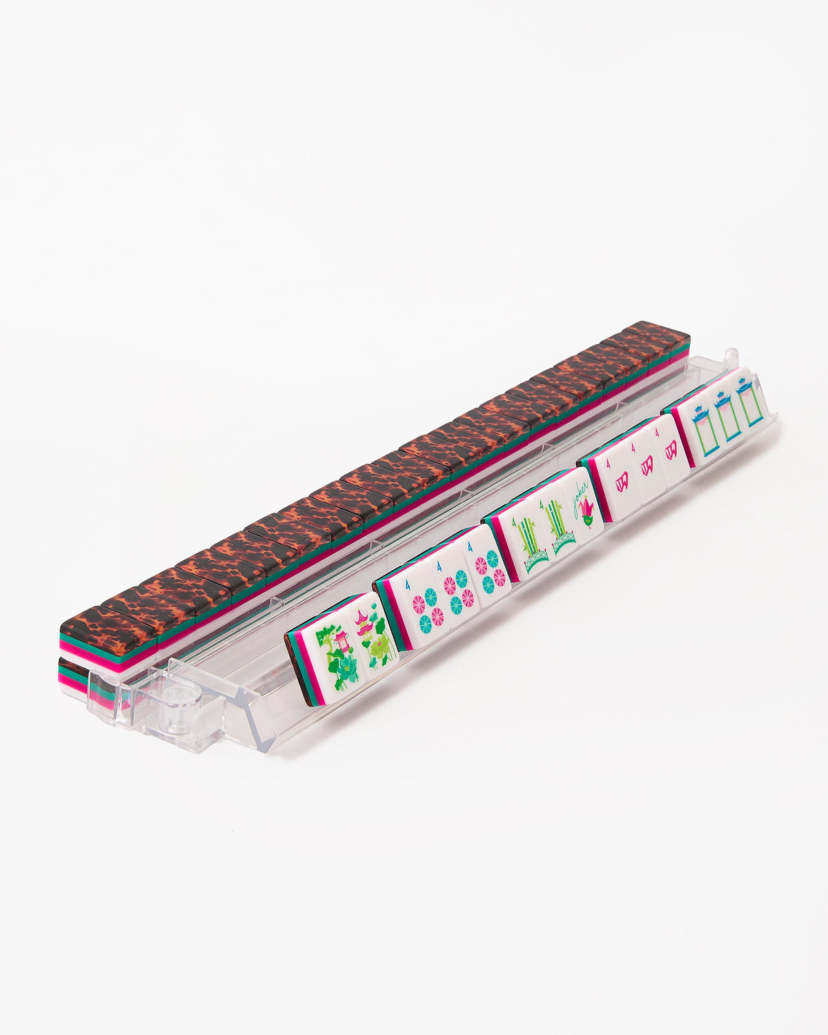 Glow Wild mahjong tiles on a clear acrylic rack, a row of face-up tiles in front and tortoiseshell tile backs lined up behind