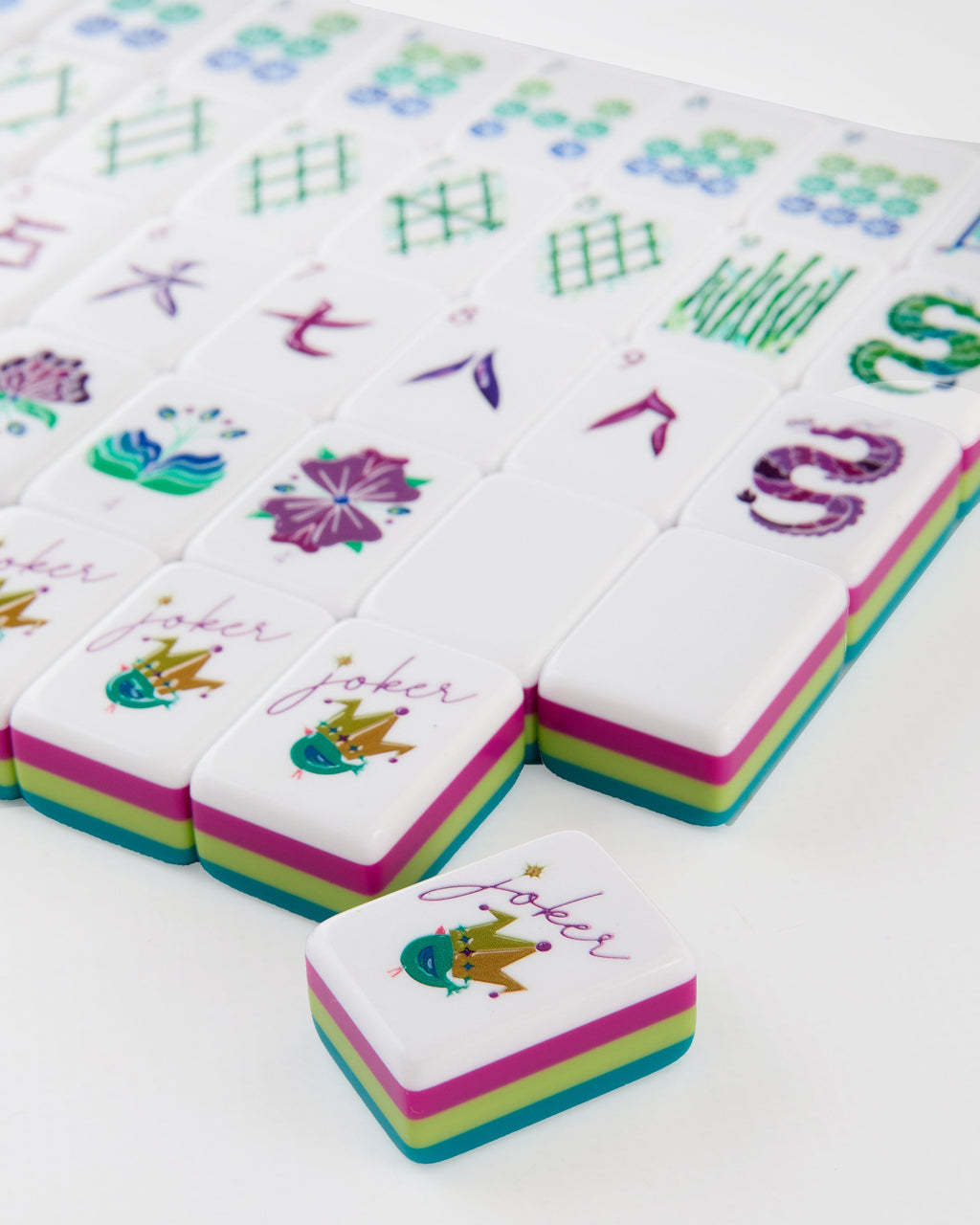 Close-up of Lagoon joker tiles with a small crowned bird, showing the layered teal, citron, and magenta tile edges