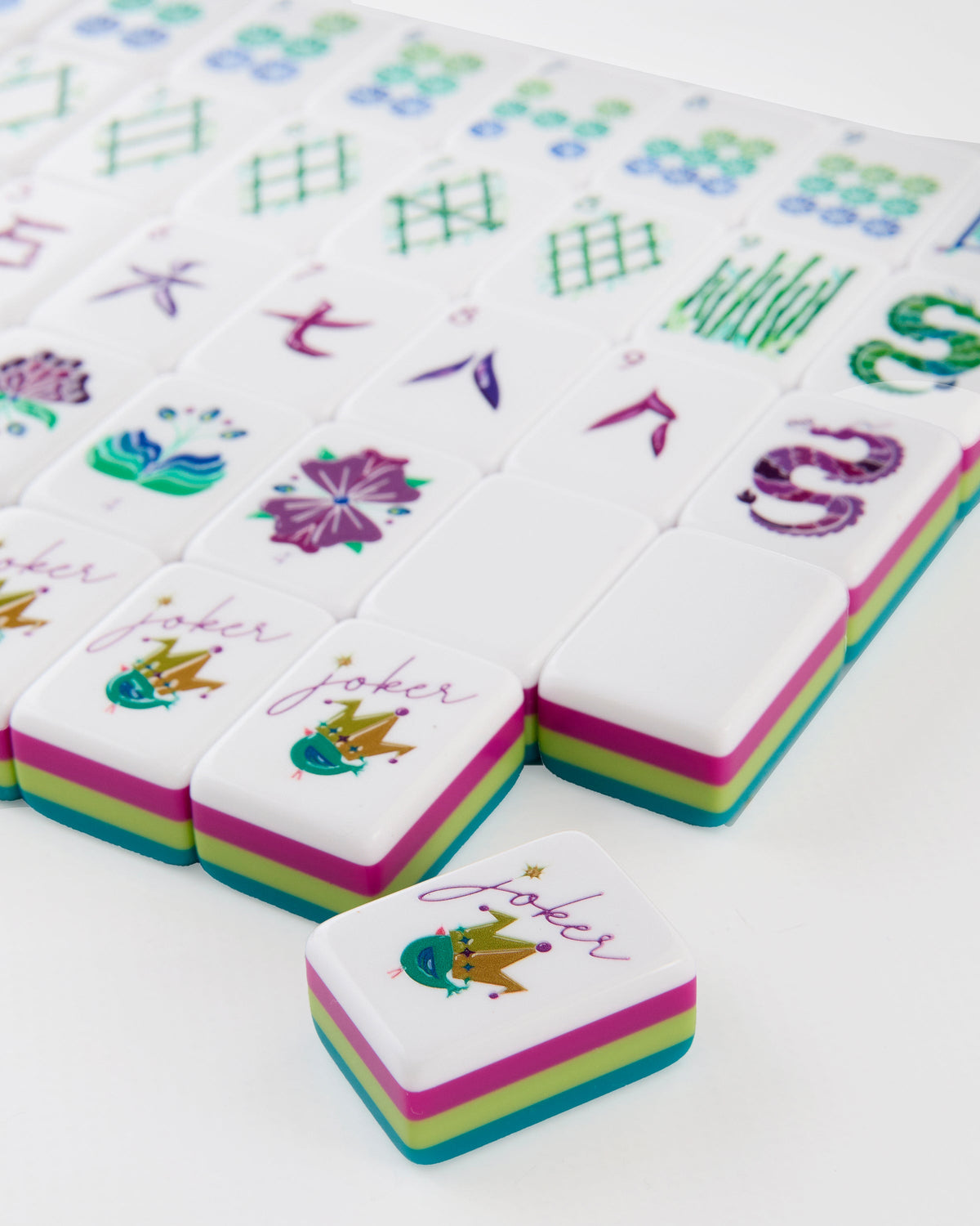 Close-up of Lagoon joker tiles with a small crowned bird, showing the layered teal, citron, and magenta tile edges