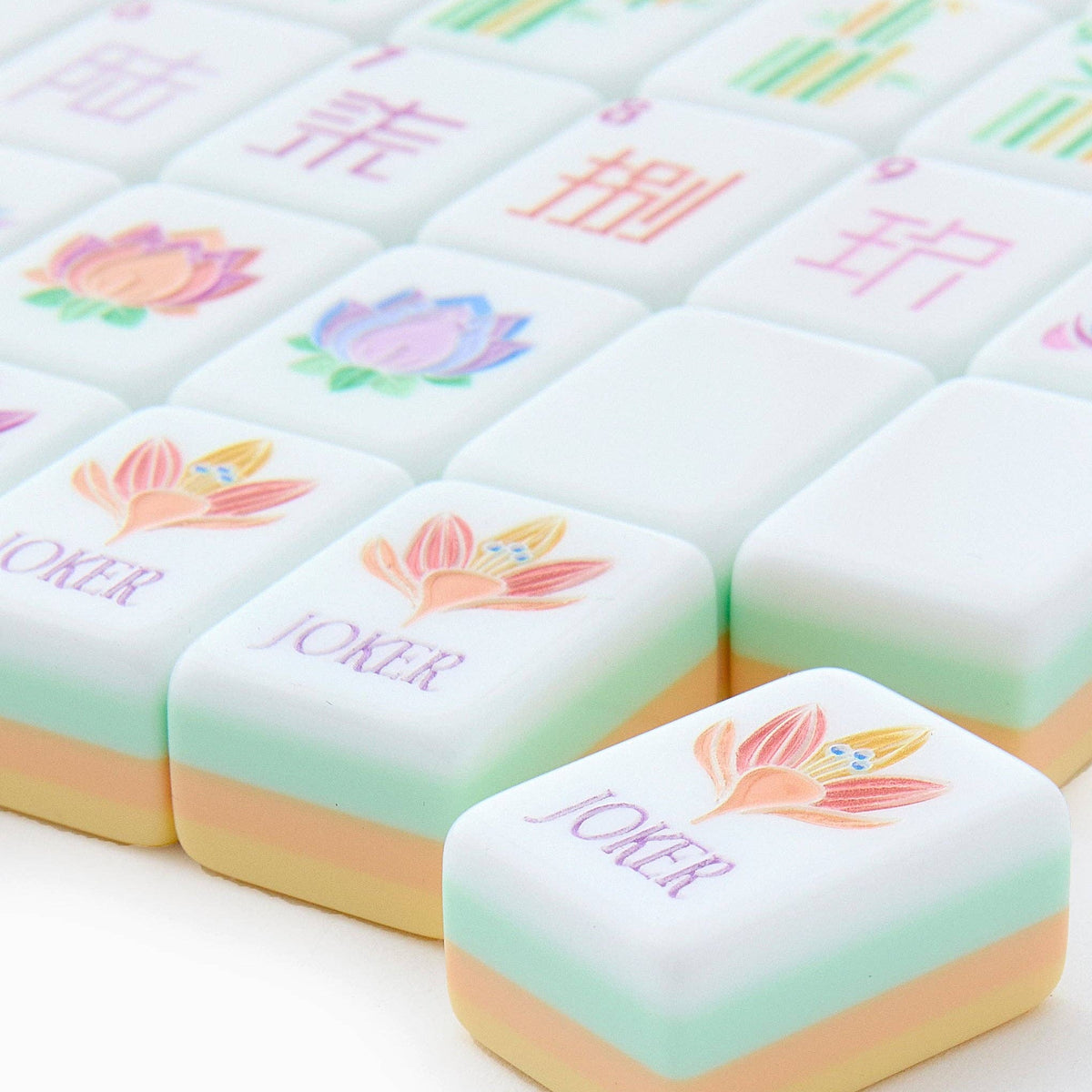 Close-up of Sorbet joker tiles with a pastel lotus flower, showing the layered turquoise, peach, and butter yellow tile edges