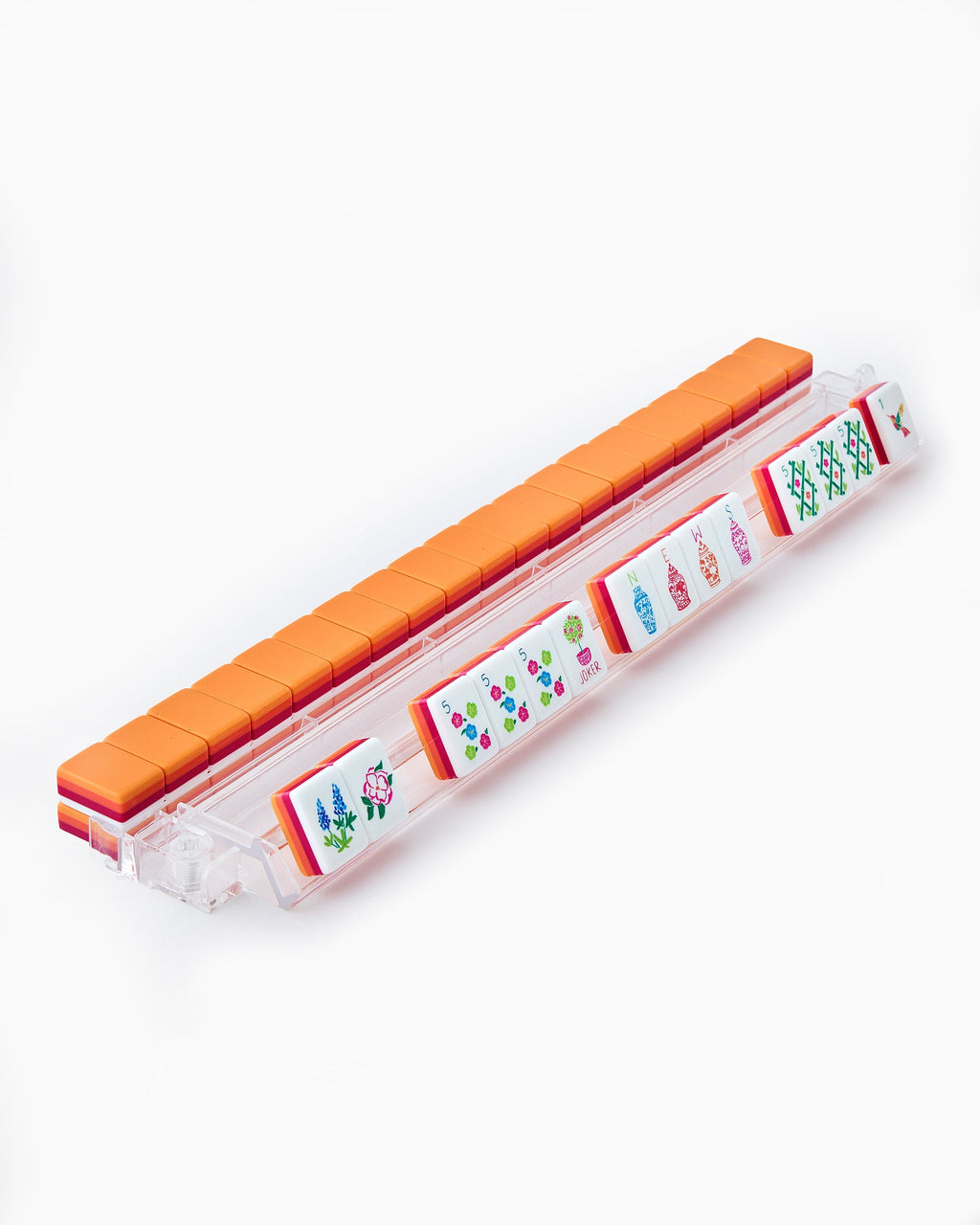 Sunset mahjong tiles on a clear acrylic rack, a row of face-up tiles in front and orange tile backs lined up behind