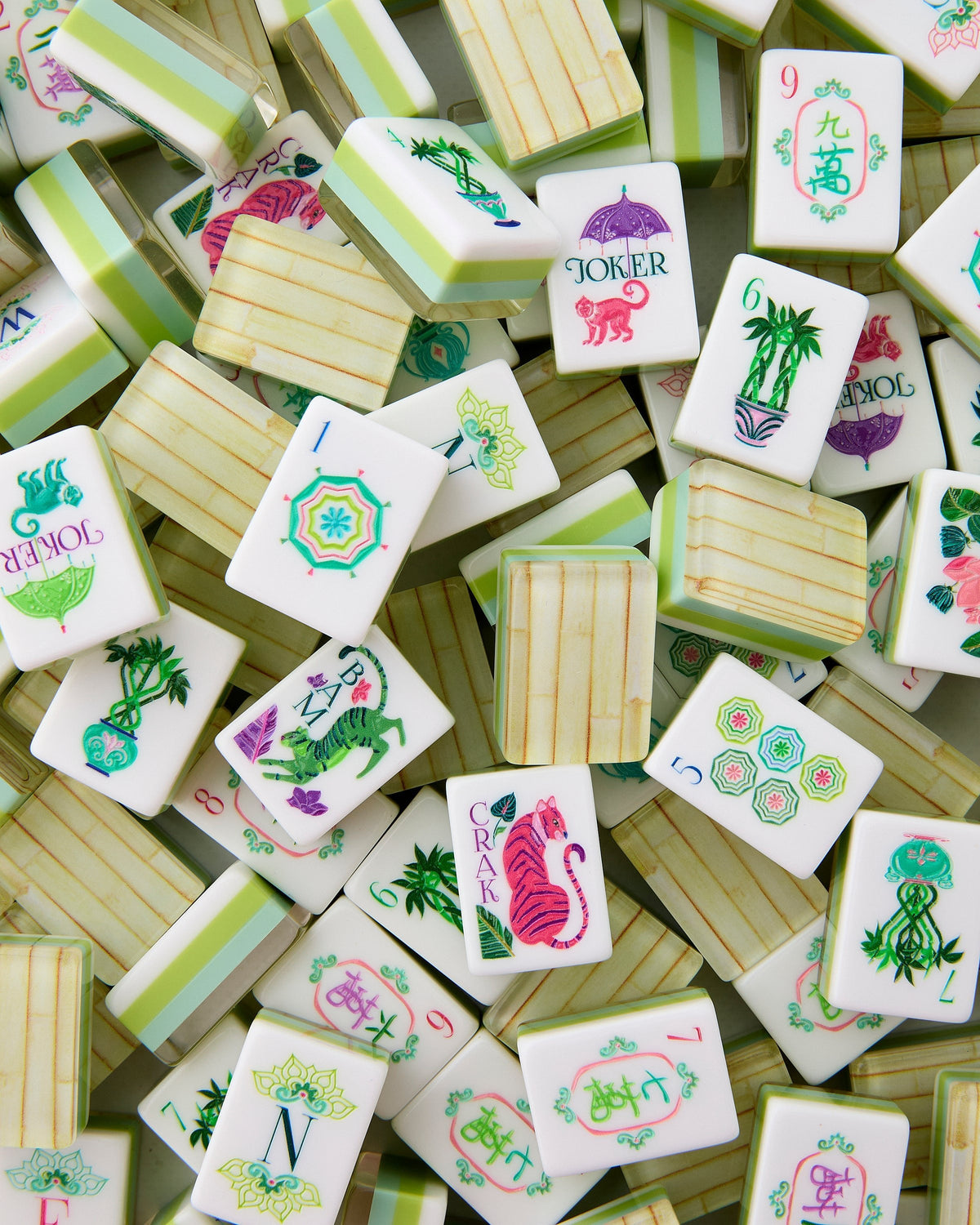 Oh My Mahjong Palm Royale tiles piled loosely, bamboo-look backs striped with green and aqua beside white tile faces
