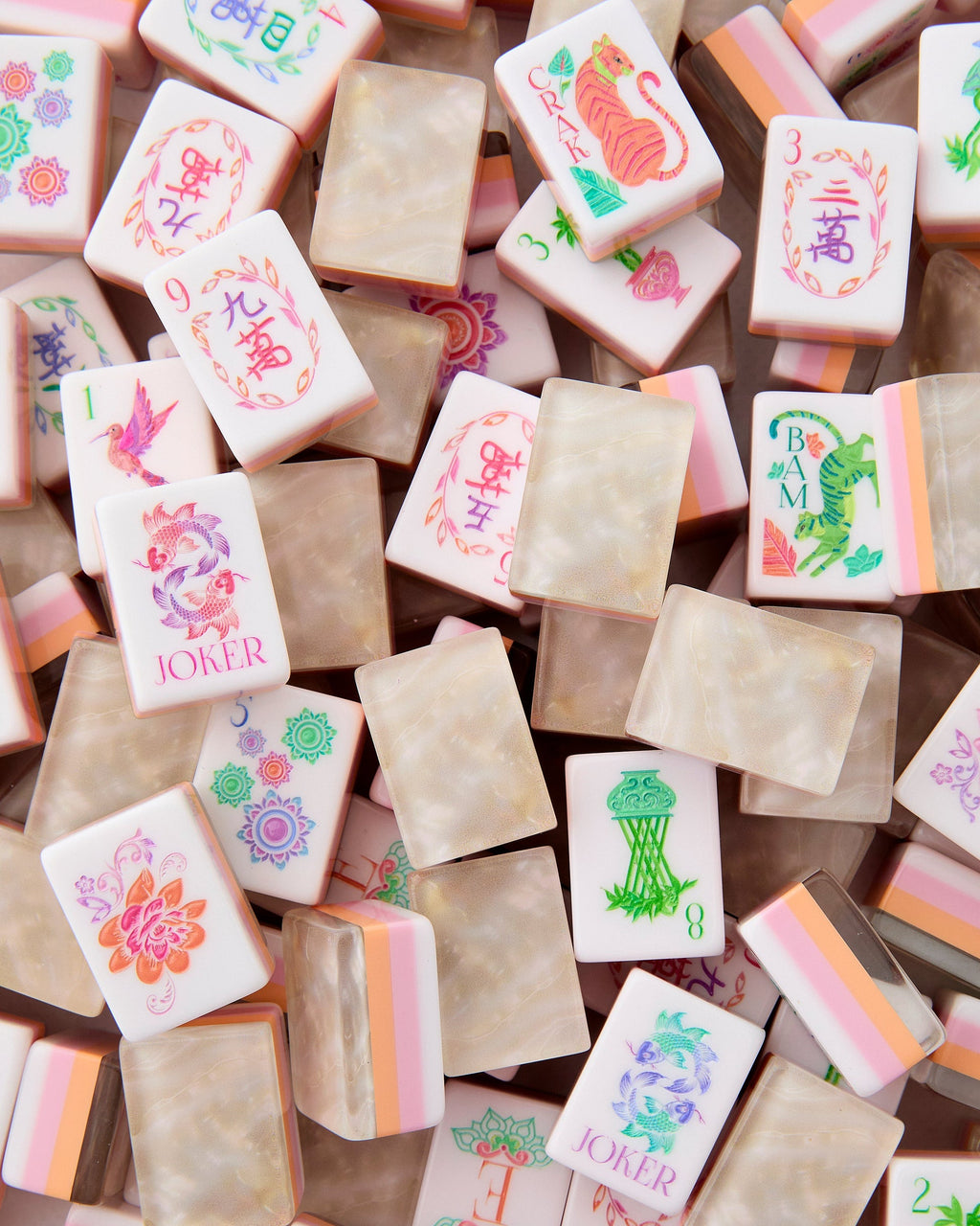 Oh My Mahjong Pearlescent tiles piled loosely, mother-of-pearl backs striped with blush and peach beside white tile faces