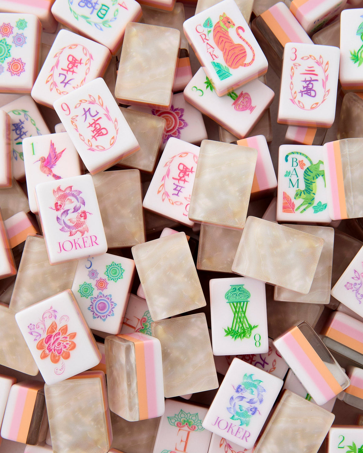 Oh My Mahjong Pearlescent tiles piled loosely, mother-of-pearl backs striped with blush and peach beside white tile faces