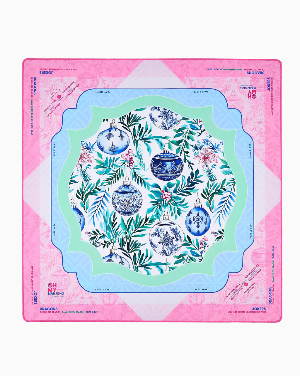 Oh My Mahjong Merriment holiday mahjong mat laid flat, evergreen sprigs and ornaments in pink, icy blue, and mint